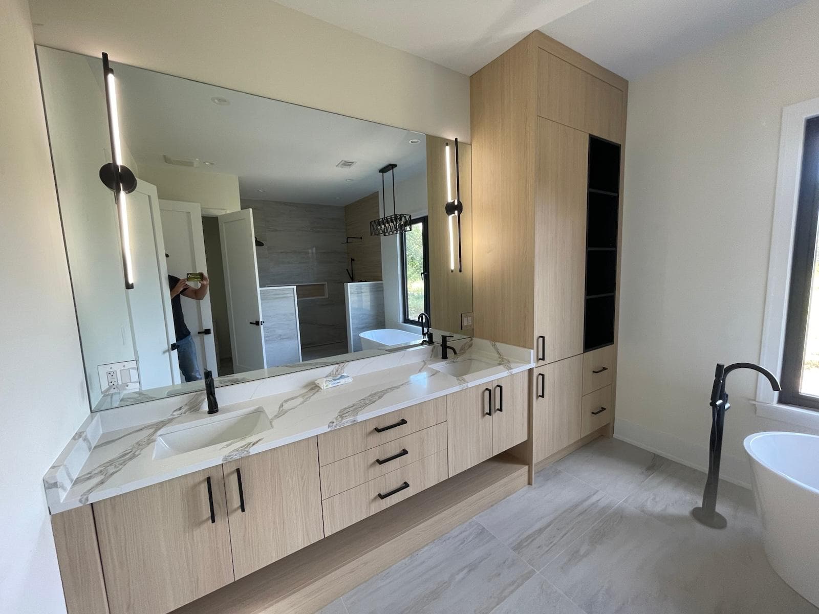 White oak floating double vanity with LED wall sconces and vessel sinks — modern bath design